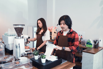 two coffee shop waiter and barista working in their cafe
