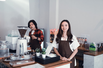 beautiful asian cafe owner smiling to camera in her coffee shop