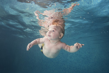 Little baby boy learning to swim underwater in a swimming pool. Healthy family lifestyle and...