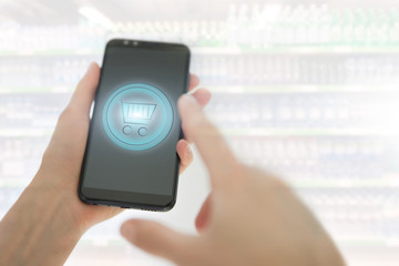Shopping basket on a mobile phone screen. Woman Hand holding mobile phone on Supermarket blur background