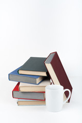 Open book, hardback colorful books on wooden table, white background. Back to school. Cup. Copy space for text. Education business concept.