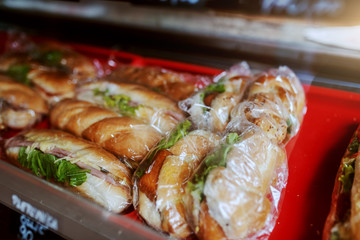 Close up of delicious fresh sandwiches in foil ready for sale. Bakehouse interior.