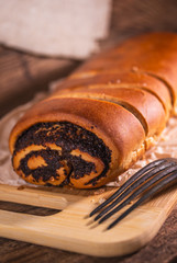 Poppy seeds roll, homemade cake on rustic wooden background