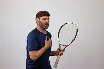 Portrait of handsome young man playing tennis holding a racket with brown hair scared, facing...
