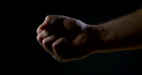 a man squeezes his hand in the dark. strong male grip