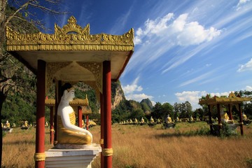 Lumbini Garden, Hpa An, Myanmar: View on secluded isolated valley with over 1000 sitting buddha statues in rows contrasting with blue sky and drifting cirrus clouds