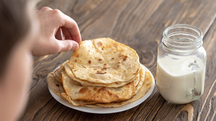 a man is having Breakfast, a mug of milk and a plate of fried corn tortillas on a wooden textured table looking over his shoulder. free text copy space