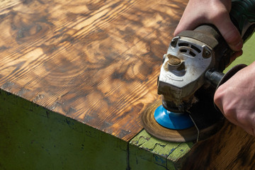 background grinding wood surface grinder with abrasive wheel. worker carpenter grinds the wood...