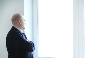 pensive businessman looking at a blank office window