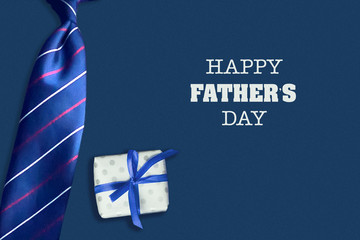 Fototapeta na wymiar Happy father's day background. The inscription on a dark background with a gift and tie. Congratulatory background.