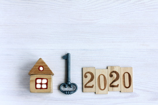 Flat lay with key, home and wooden numbers on the wooden table, top view. Detached house in 2020