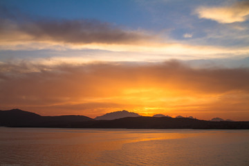 Fototapeta premium Sunrise on the Sardinian sea coast with intense orange color seen from the sea