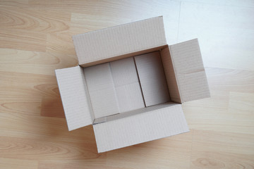 topview of empty cardboard box on laminate floor