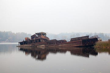 Old sunken ship in water in a foggy day