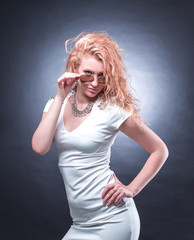 Obraz premium fashionable blonde woman in white dress looking through sunglasses
