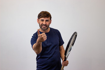 Portrait of handsome young man playing tennis holding a racket with brown hair clapping hands,...