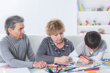 grandma and grandpa are drawing a rainbow with their grandson