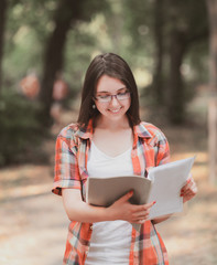 Obraz premium smiling student girl with a clipboard on the background of the Park