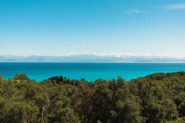 Fototapeta premium View from Cape Drastis (Peroulades) towards Albania and its mountains with crystal clear blue water on a sunny summer day (Corfu, Greece, Europe)