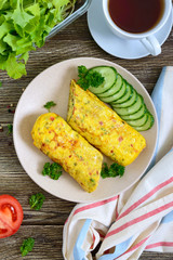 Omelette, egg roll with vegetables and herbs on a wooden table. Delicious healthy breakfast. Top view.