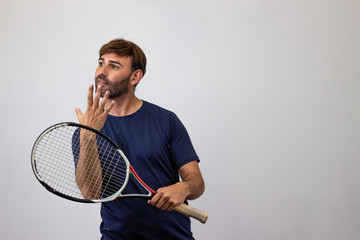 Portrait of handsome young man playing tennis holding a racket with brown hair holding up seven...