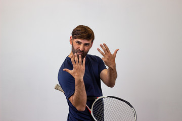 Portrait of handsome young man playing tennis holding a racket with brown hair making a stop sign...