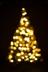 Golden Christmas tree with decorations and lights bokeh in a black background
