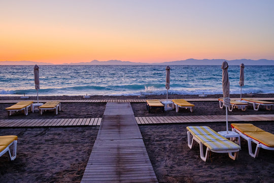 sandy beach with sunbeds in the foreground, sea and mountains in the background