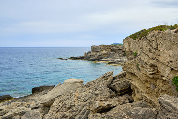 cliffs by the sea in the foreground and large cliff in the background, overcast weather