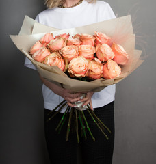 A beautiful bouquet of flowers of roses, salmon and orange colors, in the hands of a girl in gold...