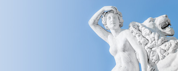Banner of an ancient statue sensual Renaissance Era woman laying on big lion with blue sky gradient background in Potsdam, Germany, details, closeup © neurobite