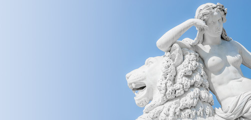 Banner of an ancient statue sensual Renaissance Era woman laying on big lion with blue sky gradient...