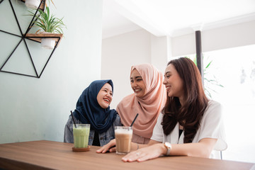 two asian muslim woman bestfriend together in cafe smiling to camera