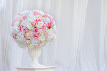 Soft home decor, white vase with white Pink flowers on a white Fabric scene background and on a Wooden platform. Interior and Exterior decoration. 