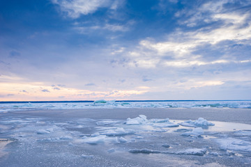 Obraz premium Beach in wintertime. Frozen sea, evening light and icy weather on shore like fairy tale country. Winter on coast. Blue sky, white snow, ice covers the land.