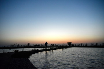Fototapeta premium Silhouette Man and Baby at Lake on the sunset at Al Qudra love lake, Dubai, United Arab Emirates