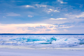 Naklejka na ściany i meble Beach in wintertime. Frozen sea, evening light and icy weather on shore like fairy tale country. Winter on coast. Blue sky, white snow, ice covers the land.