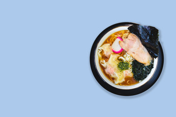 Isolated top view of Ramen Pork Bone Soup (Tonkotsu Ramen) with Chashu Pork, Scallion, Wanton, Menma (Seasoned Bamboo Shoots), Dried Seaweed on the right side in blue background copy space.