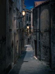 Streets of Tropea in Italy in dark night or evening. Bright lanterns lamps lit up the old buildnings and narrow pathways.