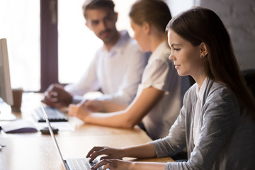 Focused young employee working on computer sitting at shared office