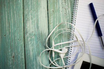 phone headphones, notebook, tablet and pen on the desktop