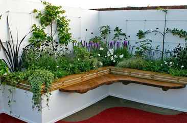 Raised corner of a terrace garden with seating, flower and fruit planting