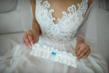 The bride in white dress and her wedding garter