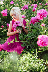 Outdoor close up portrait of beautiful young woman with long blonde hair, makeup, posing in the blooming garden. Female spring fashion concept