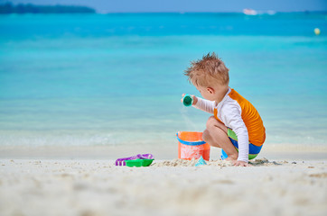 Three year old toddler playing on beach