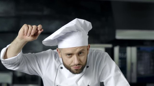 Chef man posing at professional kitchen. Male chef preparing to cook at kitchen.