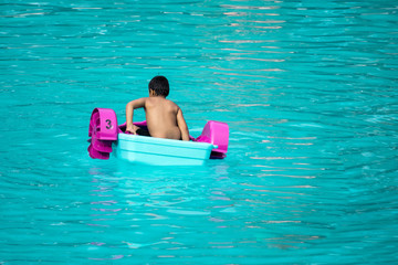 Child playing a water pedal boat in a swimming pool