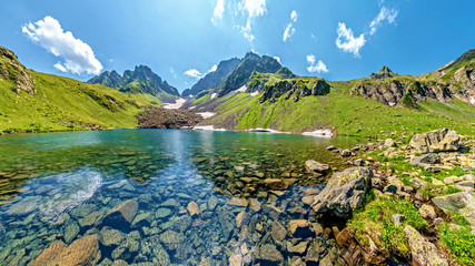 Fototapeta na wymiar Turquoise water in lake Kalalish with peaks in background, Svaneti mountains, Georgia, Asia