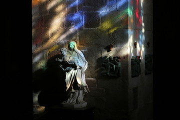 Glare from sunlight passing through the stained glass windows, paint the interior of the church and the sculpture of the Madonna and Child (Saint-Malo, France)