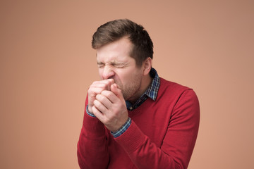 Handsome mature manin red sweater coughing a lot.